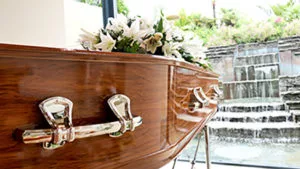 Wooden casket with silver handles and white flowers, illustrating a Georgia wrongful death claim