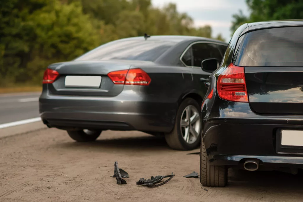 A photo of a car accident between two cars. There is debris from the crash on the ground.
