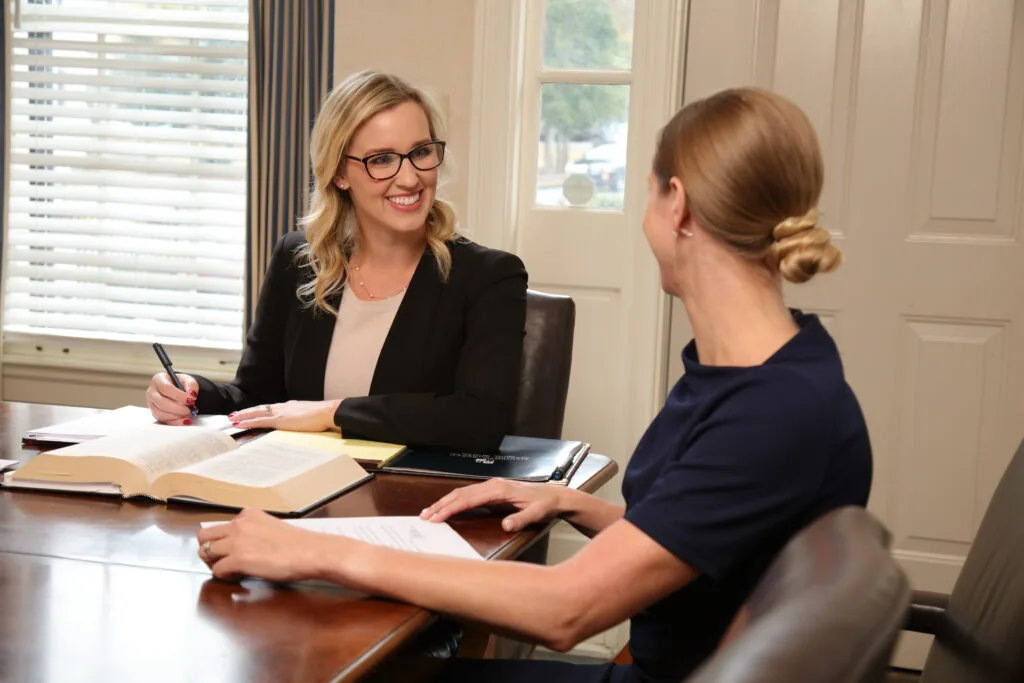 A photo of a BBGA Attorney at a conference table with a client. She is smiling at the client as they discuss a tax & estate case.