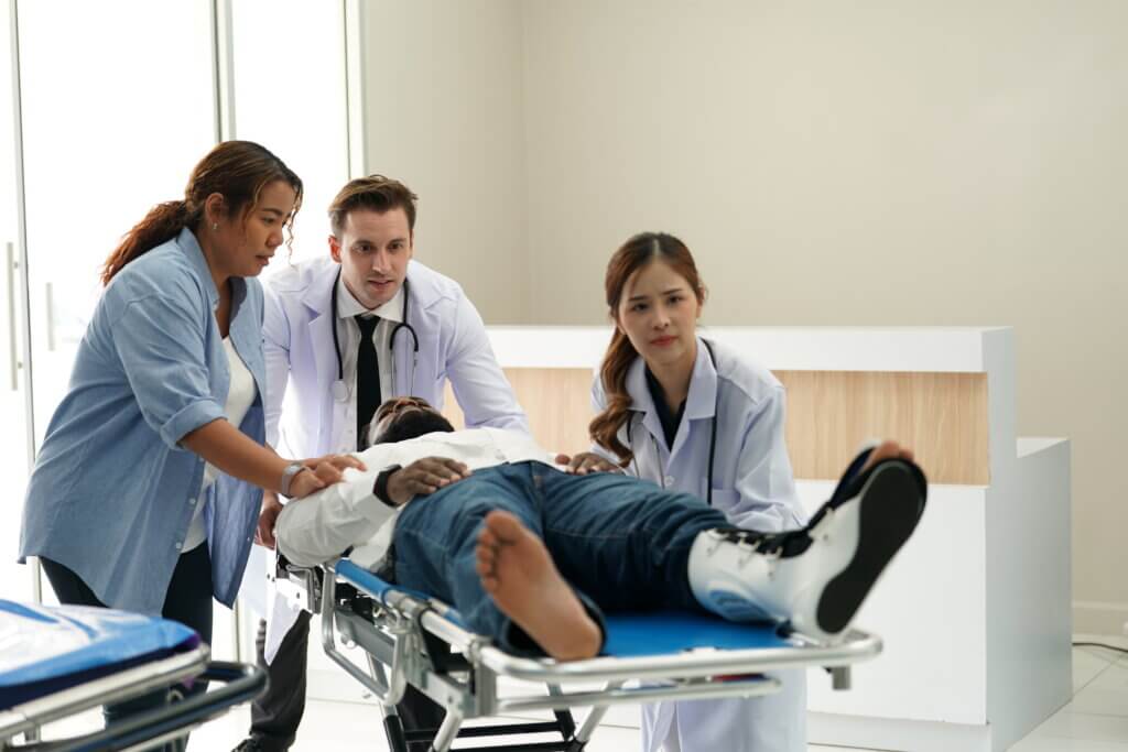 Hospital staff push an injured man on a gurney through hospital doors.