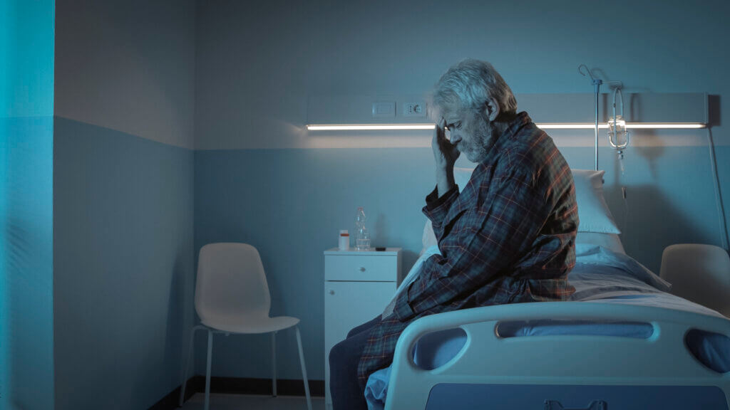 Lonely elderly resident sitting on a bed at night, illustrating Barrow County nursing home neglect concerns